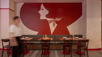 A restaurant with a large wall mural, booths, and tables with chairs.