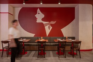 A restaurant with a large wall mural, booths, and tables with chairs. - Hotel Indigo Sydney Potts Point (Sydney)