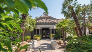 A Mediterranean-style building with a tiled roof, surrounded by palm trees and a gravel pathway leading to the entrance. - Luxury Comfort close to Westworld & TPC + Pool&Spa (Scottsdale)
