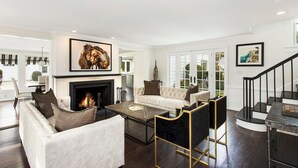 A spacious living room with a fireplace, a sofa set, a coffee table, and a staircase.