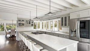 A modern kitchen with a large island, stainless steel appliances, and a view of the outdoors.