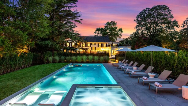 A swimming pool with lounge chairs and a well-lit patio area.