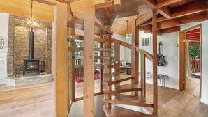 Una escalera de madera con un diseño interior rústico, una chimenea de piedra y una guitarra en la pared.