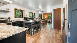 Una cocina moderna con una isla grande, suelo de madera y vistas al exterior a través de amplios ventanales.