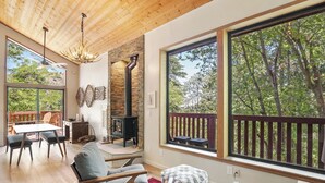 Un salón espacioso con chimenea de piedra, ventanas amplias y techo de madera.