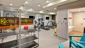 Una palestra con tapis roulant, macchine ellittiche e una cyclette. Si vede uno specchio con un cartello che riporta la scritta "2 CYCLE".
