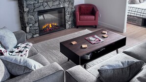 Un salon moderne avec une cheminée en pierre, un téléviseur à écran plat fixé au-dessus et un fauteuil rouge.