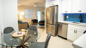 A modern kitchen with white cabinets, a stainless steel refrigerator, and a blue tiled backsplash.