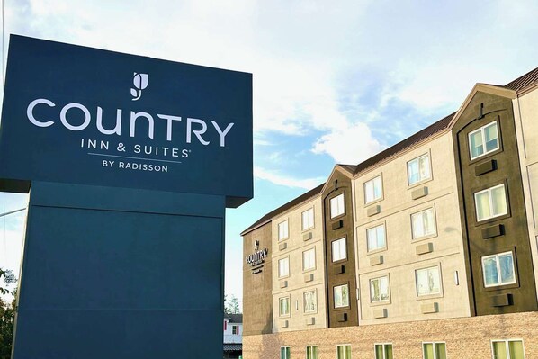 A Country Inn & Suites sign and a building with multiple windows and a brick facade. - Country Inn & Suites by Radisson, Rehoboth Beach - Dewey (Rehoboth Beach)