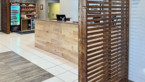 A reception area with a wooden reception desk, a vending machine, and a counter with snacks. - Country Inn & Suites by Radisson, Rehoboth Beach - Dewey (Rehoboth Beach)