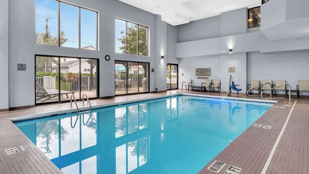 A modern indoor pool with clear glass walls, a lifeguard station, and a view of the outside. - Country Inn & Suites by Radisson, Rehoboth Beach - Dewey (Rehoboth Beach)