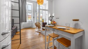 Una cocina moderna con una mesa de madera, taburetes de bar, una lámpara colgante y vistas de la ciudad a través de amplios ventanales.
