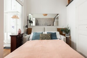 Un dormitorio con cama, cómoda, espejo, lámpara y planta en maceta.