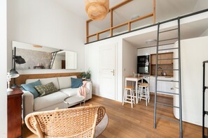 Un apartamento estilo loft con comedor, cocina y un ventanal grande.