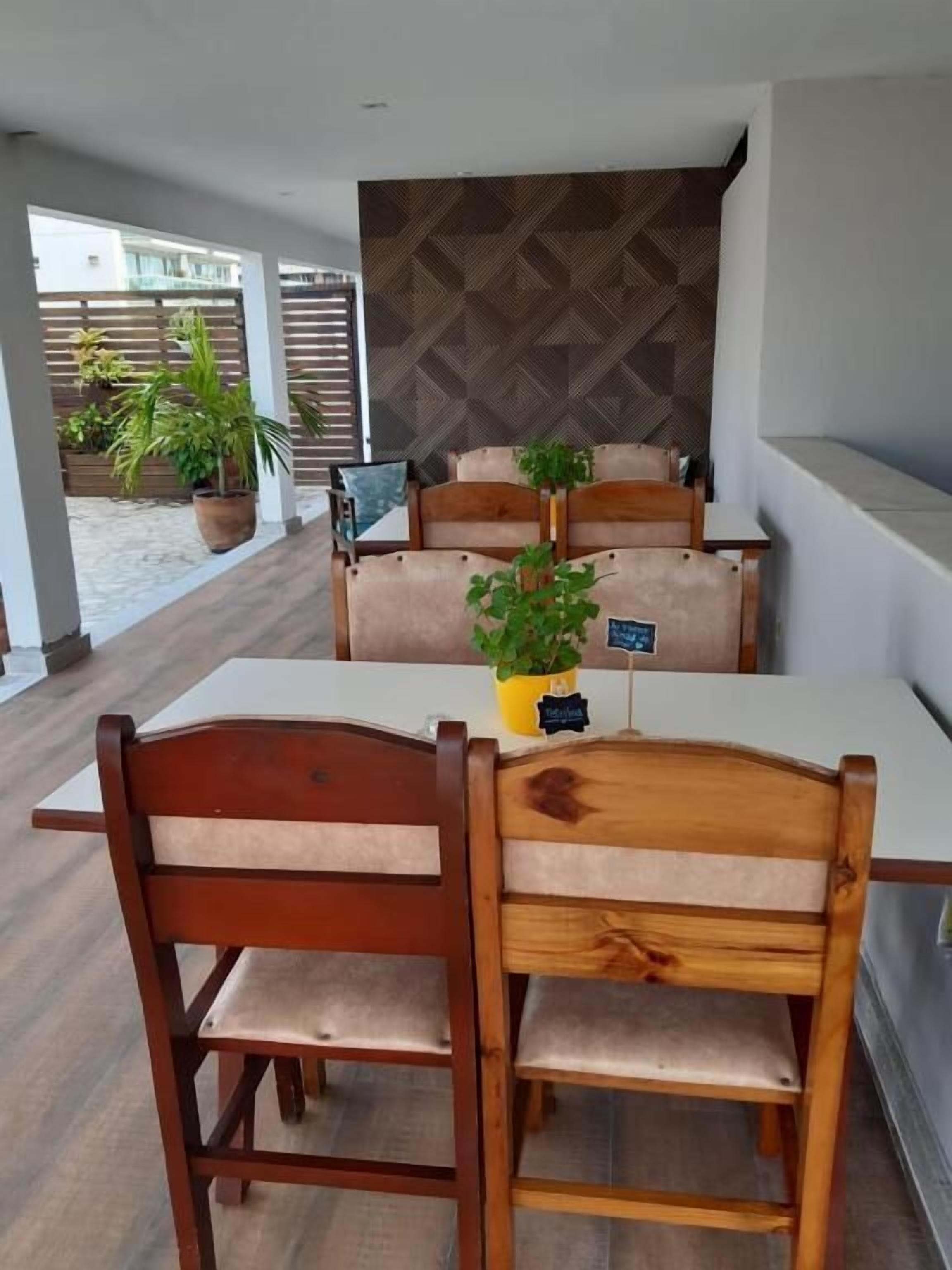 A dining area with a white table and wooden chairs, a potted plant, and a geometric-patterned wall.