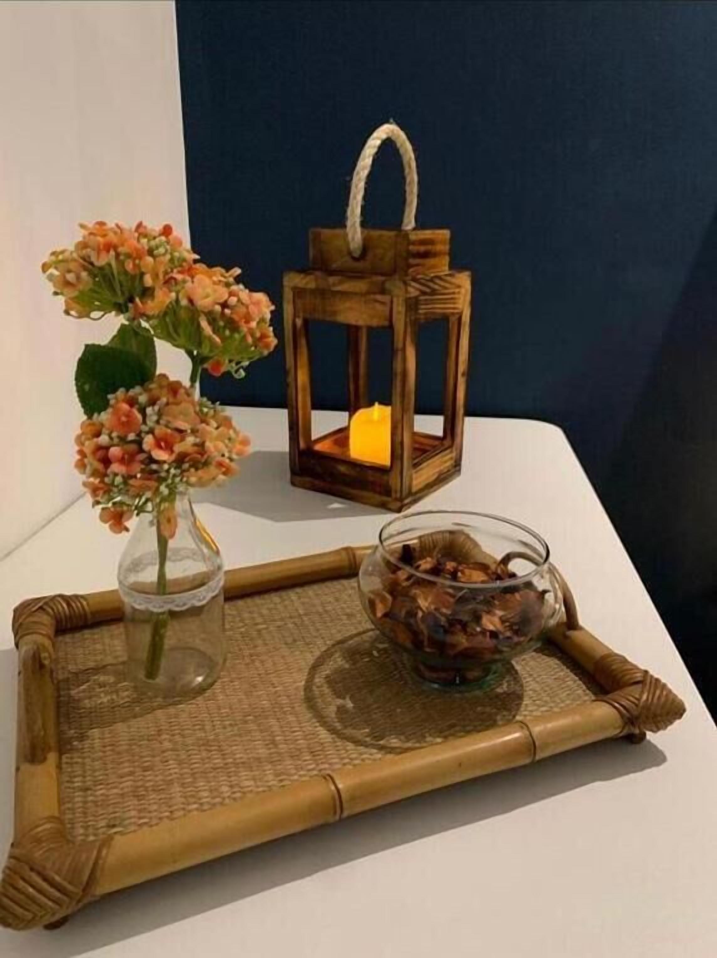 A tray with a glass vase of flowers, a lantern, and a bowl of dried flowers.