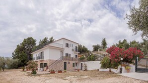 Una casa de dos pisos con fachada de piedra, un balcón y una escalera que lleva al nivel superior.