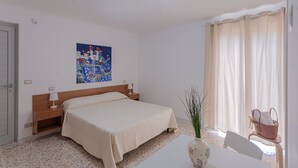 Habitación de hotel con cama, mesita de noche, lámpara y un cuadro en la pared.