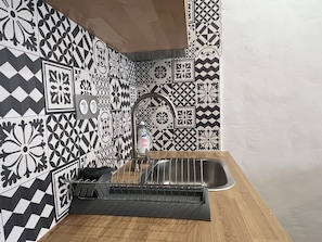 A kitchen with a stainless steel sink, a soap dispenser, and a black dish rack.
