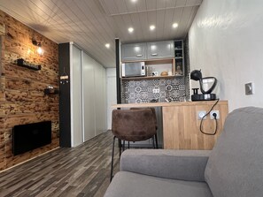 A modern kitchen with a wooden wall, a built-in microwave, and a coffee machine.