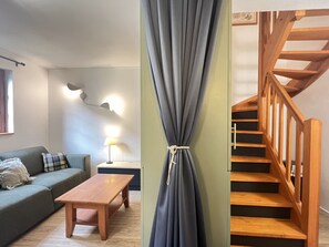 En stue med sofa, træbord, lampe og trappe med træsider.
