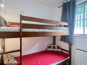 A bunk bed with a red mattress and a pillow with animal prints.