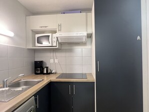 A compact kitchen with a microwave, coffee maker, and a sink.