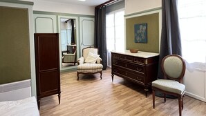 Un dormitorio con un armario de madera, un tocador, una silla y una cama.