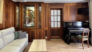 Una sala de estar con un piano, un sofá, una mesa de centro y paneles de madera en las paredes.