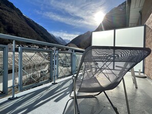 Ein stuhl mit Metallgestell und Mesh-Rückenlehne auf einem Balkon mit Blick auf eine gebirgige Landschaft.