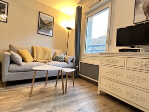 Un salon avec un canapé, une table basse, un téléviseur et une commode.