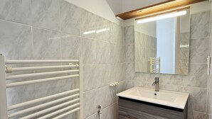 Un baño con lavamanos blanco, espejo y barra para toallas.