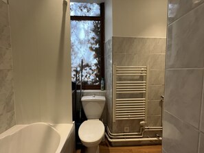 A bathroom with a bathtub, toilet, and a glass shower enclosure.