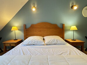 A bedroom with a wooden headboard, two bedside lamps, and a bed with white bedding.