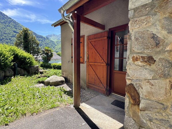 A stone building with a wooden door and a metal roof gutter. - Duplex 40m2. Balcon. Parking. 5P (Cauterets)