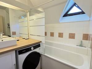 A modern bathroom with a built-in washing machine, a sink, and a bathtub.
