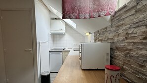 Eine kleine Küche mit einer Holz Arbeitsplatte, einem weißen Kühlschrank und einer Mülltonne.