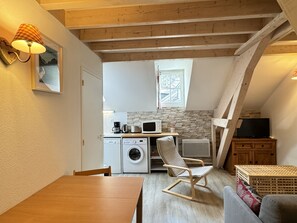 A compact kitchen with a washing machine, microwave, and coffee maker. - ROYAL19 (Cauterets)