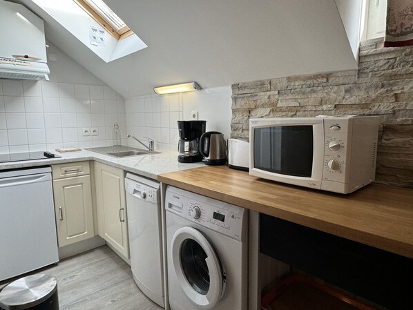 A compact kitchen with a washing machine, a microwave, and a coffee maker.
