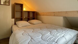 Ein Einzelbett mit weißer Daunendecke, einem hölzernen Kopfteil und einem Nachttisch mit Lampe.