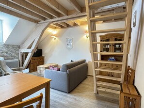 Une pièce de style loft avec une table en bois, un canapé gris et une échelle en bois.