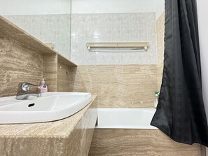 A bathroom with a white sink, a mirror, a shower curtain, and a towel rack.