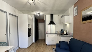 A compact living space with a kitchenette, a dining area, and a sofa. - Joli 3 pièces 40m2. 2 chambres (Cauterets)