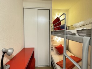 Een slaapkamer met een stapelbed, bureau en lamp.