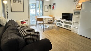 Un espace de vie moderne comprenant un canapé, une table à manger, des chaises, un téléviseur et un réfrigérateur.