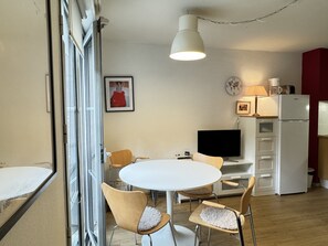 A compact living space with a dining area, a kitchenette, and a TV.