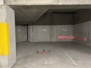 A parking garage with concrete walls, numbered parking spots, and a yellow safety line on the left. - 100m télécabine ou commerces. 4P (Cauterets)