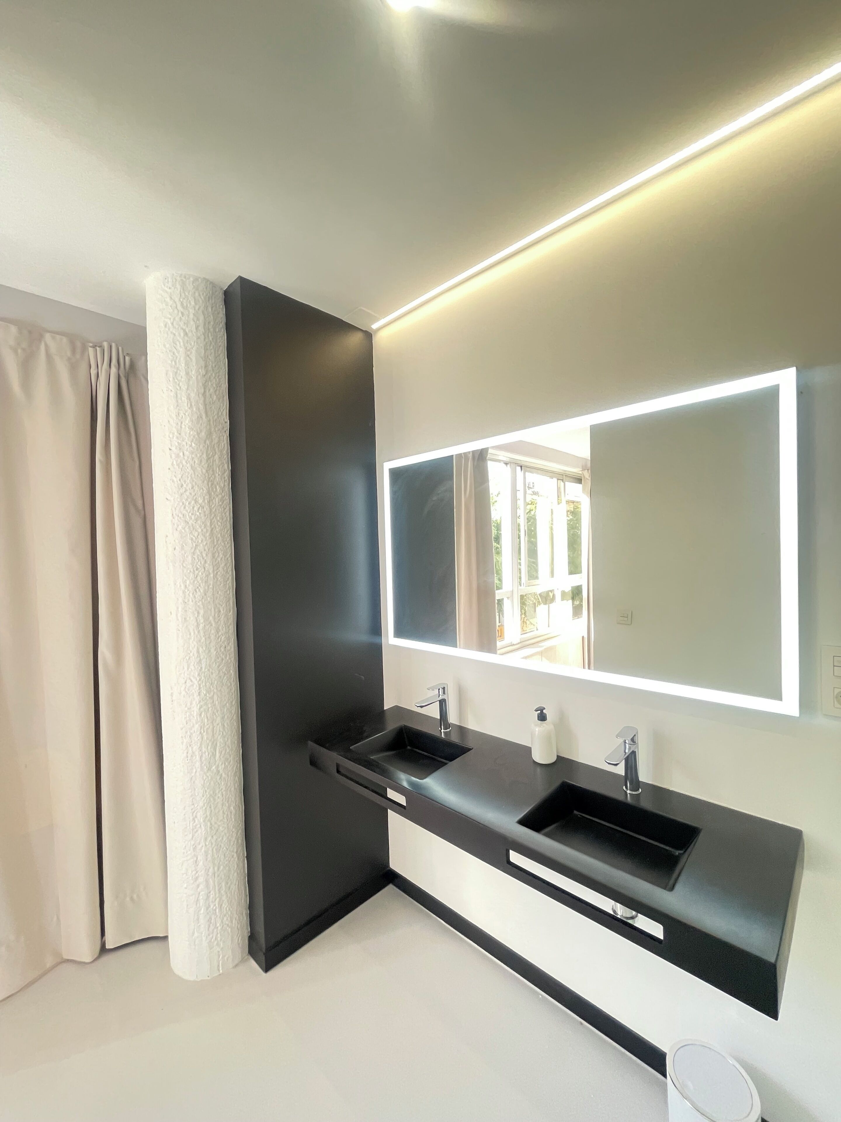 A modern bathroom with a black sink, a large mirror, and a white towel.