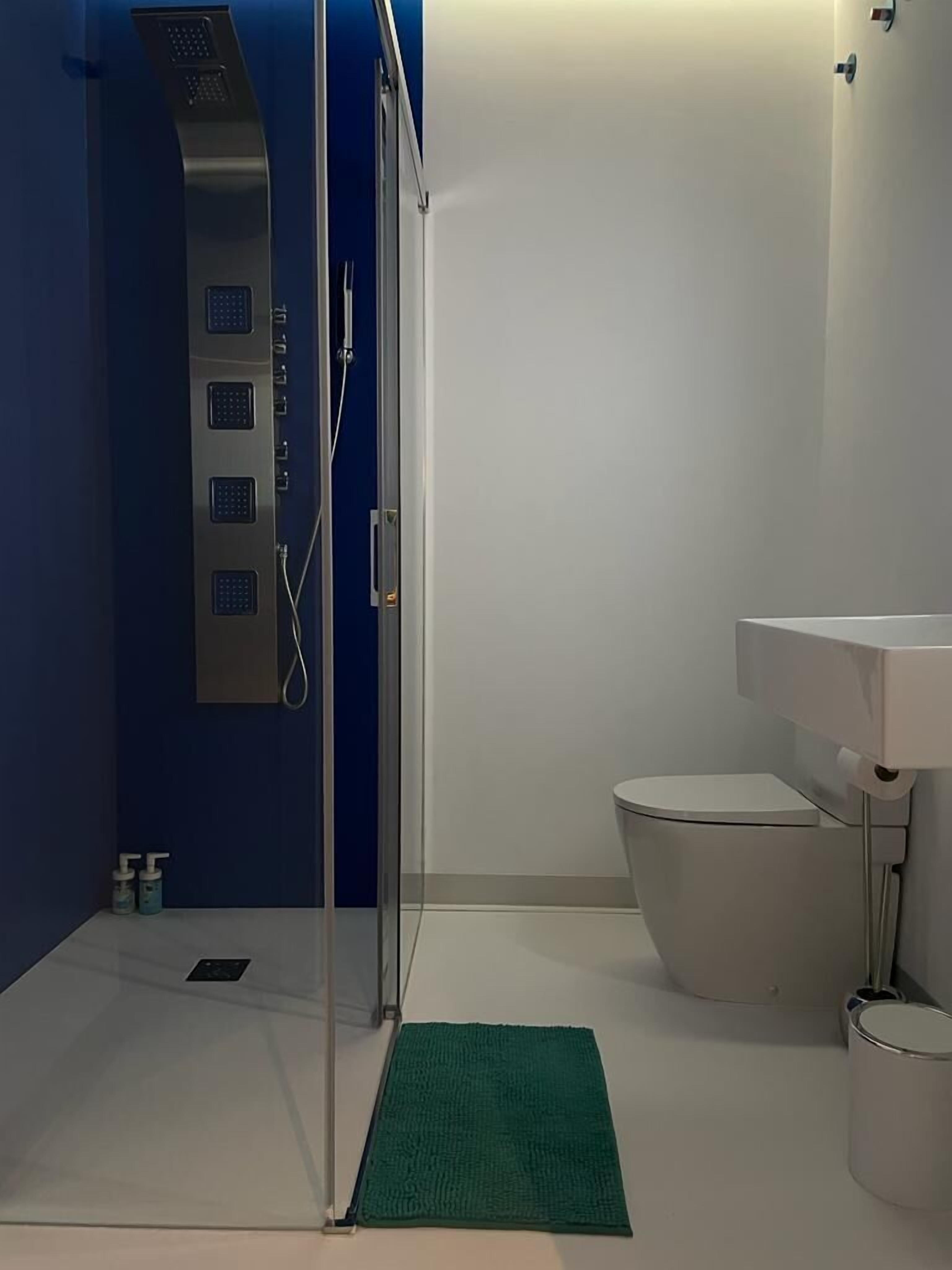 Ein modernes Badezimmer mit Duschkabine aus Glas, einer weißen Toilette und einem Waschbecken mit Spiegel.