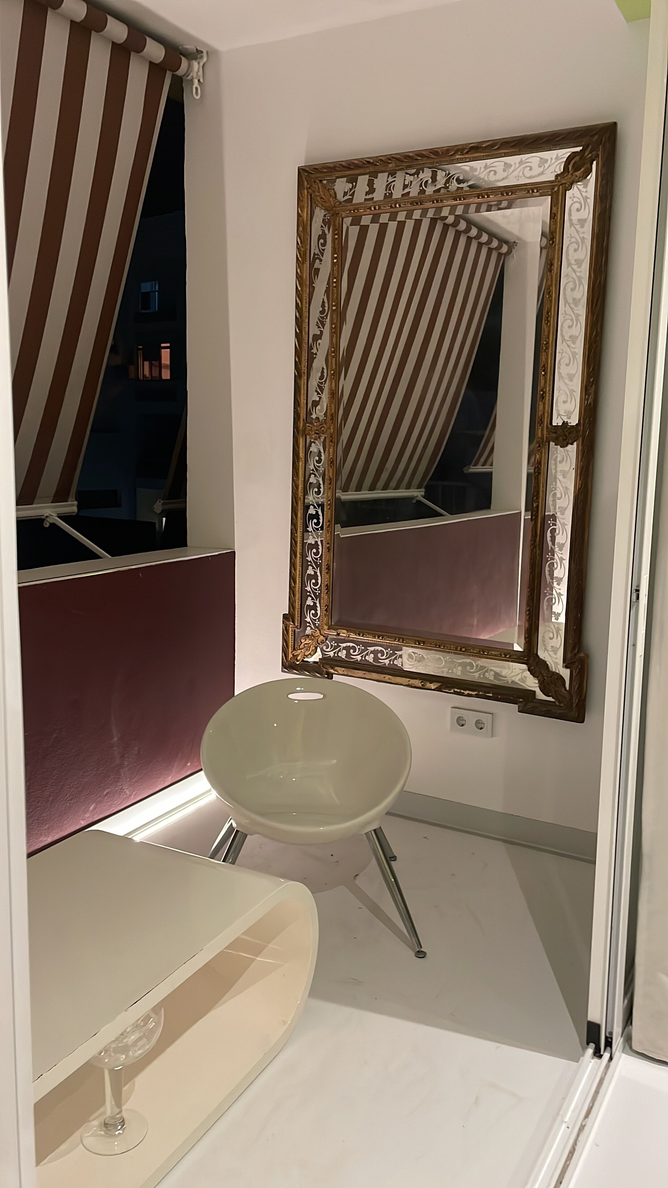 A bathroom with a white sink, a large mirror with an ornate frame, and a striped curtain.